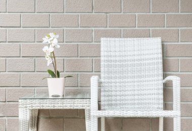 Bulanık kahverengi tuğla duvar dokusu arka plan üzerinde ahşap örme sandalye ile ahşap örme masada pembe çiçek üzerinde beyaz orkide çiçek ile Closeup yapay bitki , gevşeme kavramı güzel iç