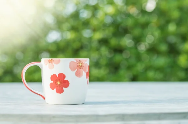Nahaufnahme niedliche Tasse Kaffee auf verschwommenem Betontisch und Blick auf den Garten am Morgen strukturierten Hintergrund — Stockfoto