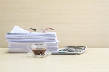 Pencere nin altındaki toplantı odasında bulanık ahşap masa ve duvar dokulu arka plan üzerinde çalışma kağıdı ve hesap makinesi yığını ile şeffaf kahve fincan ılıma siyah kahve