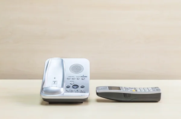 Primer plano teléfono gris, teléfono de oficina en escritorio de madera borrosa y fondo texturizado de la pared en la sala de reuniones bajo la luz de la ventana — Foto de Stock