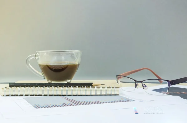 닫다 블랙 커피 노트 책에 커피의 투명 한 컵과 연필 흐리게 나무 책상과 유리 벽 질감 배경에 작업 종이, 커피 작업 용지와 안경에 의해 작업 개념 — 스톡 사진