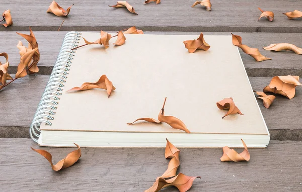Libro de notas marrón de primer plano sobre la mesa de madera en el jardín con hojas secas fondo texturizado — Foto de Stock