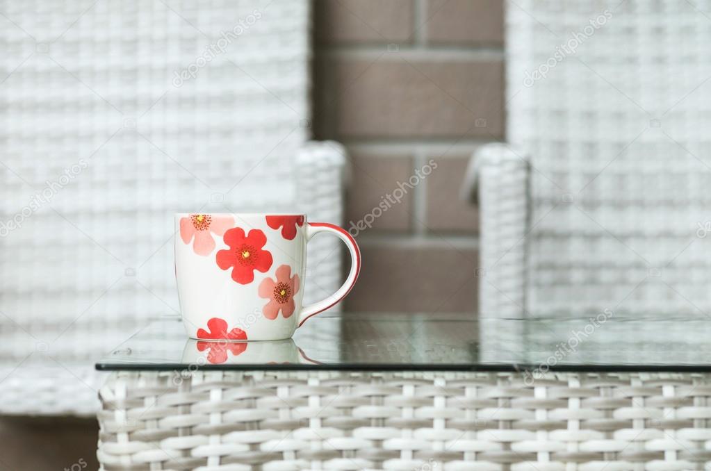 Closeup cute cup on blurred wood weave table and chair textured background