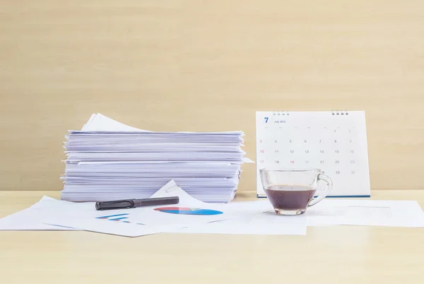 Closeup work paper with black coffee in transparent cup of coffee in work concept on blurred wooden desk and wall textured background in the meeting room under window light