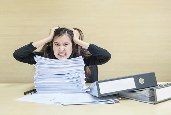 Donna che lavora da vicino sono stressati dalla carta di lavoro e file di documenti di fronte a lei in concetto di duro lavoro sulla scrivania in legno sfocato e sfondo strutturato parete nella sala riunioni sotto la luce della finestra — Foto Stock