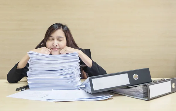 Primo piano felice donna che dorme dopo aver finito il suo lavoro con carta da lavoro e file di documenti su una scrivania in legno sfocato e sfondo strutturato a parete nella sala riunioni, donna ama il suo concetto di lavoro — Foto Stock