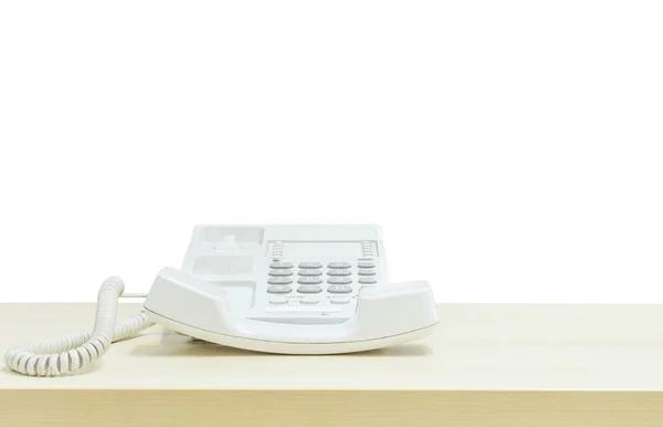 Telefono bianco primo piano, telefono ufficio su scrivania in legno sfocato nella sala riunioni sotto la luce della finestra isolato su sfondo bianco — Foto Stock