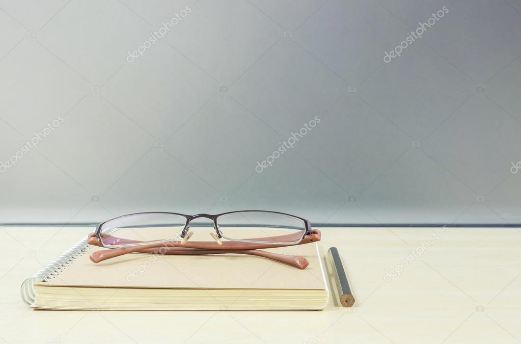 Closeup Brown Note Book On Blurred Wooden Desk And Frosted Glass