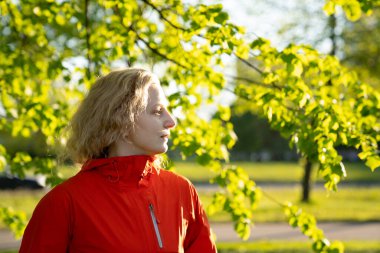Profilde beyaz saçlı ve kırmızı ceketli bir kızın portresi..