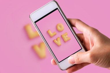 Cep telefonuyla Cookie 'nin ABC' sini pembe arka planda, Sevgililer Günü 'nde 