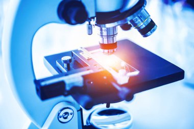 Laboratuvarda metal mercekle mikroskobun yakın çekim görüntüsü.