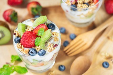 Yoğurt ve berry cam ahşap plaka zemin üzerine taze meyve salatası. Sağlıklı beslenme. Seçici odak.