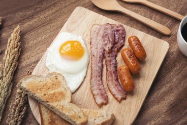 Kahve, sahanda yumurta, pastırma, sosis, ekmek ve et tabakta. Masada nefis bir kahvaltı.