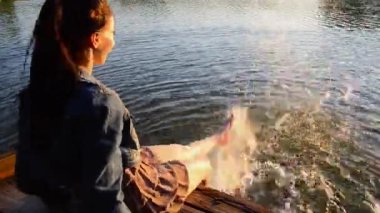 su ayaklarda oynayan kız. o su isabet sıçramaları ayak oluşturur. kısa bir elbise esmer. serpmek ayakları suda. Kadın üzerinde güneş batımından düşüyor.