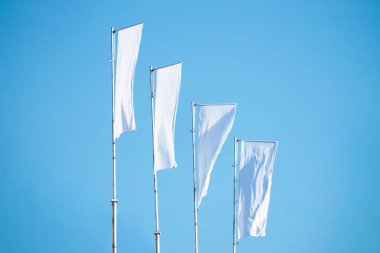 Bulutlu mavi gökyüzüne karşı bayrak direkleri üzerinde üç boş beyaz bayrak perspektif, reklam logosuna kurumsal bayrak modeli, metin veya sembol, kopyalama alanı olan şirket kimliği şablonu