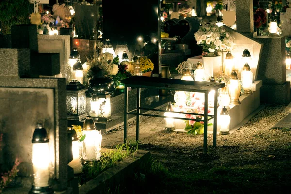 Cemetery at night, burning candles, gravestones illuminated by candlelight