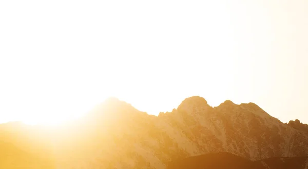 Big mountains on a background of orange sunset.