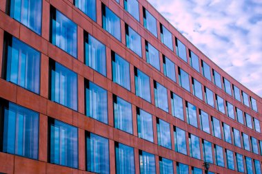Bir ofis binasının modern cam cephesi, Pencerelerde gökyüzünün yansıması.
