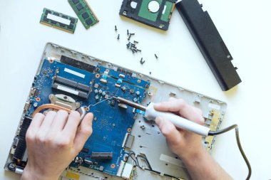 Adamın biri dizüstü bilgisayarı tamir ediyor, beyaz arka planda bir dizüstü bilgisayarı parçalıyor, ana bilgisayarı lehimliyor.