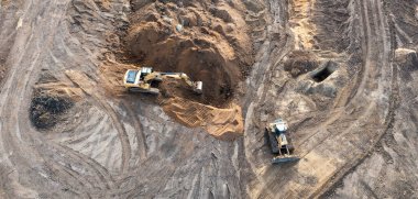 Kazıcı temelin altına bir çukur kazar ve buldozer zemini temizler. Bir inşaat alanının üst görünümü