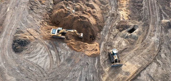 Kazıcı temelin altına bir çukur kazar ve buldozer zemini temizler. Bir inşaat alanının üst görünümü