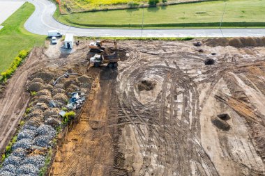 Kazıcı temelin altına bir çukur kazar ve buldozer zemini temizler. Bir inşaat alanının üst görünümü