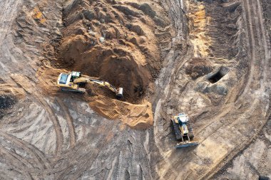 Kazıcı temelin altına bir çukur kazar ve buldozer zemini temizler. Bir inşaat alanının üst görünümü