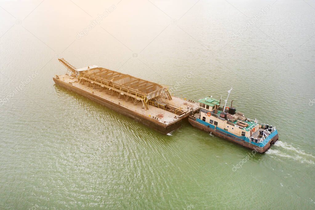 Extraction of sand from the river, excavator digs out sand from the bottom of the lake and unloads it on a floating barge, mining