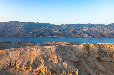 Kumlu adaların ve mavi denizdeki dağların havadan görünüşü, yaz mevsimi deniz manzarası gün batımında, Hırvatistan