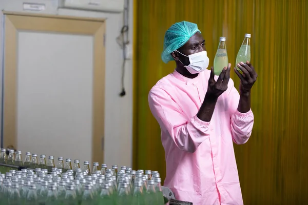 Trabajador Africano Fábrica Con Máscara Médica Revisando Mirando Botella Jugo — Foto de Stock