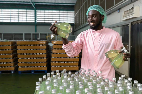 Afrykański Pracownik Fabryczny Odbierający Trzymający Butelkę Zielonego Soku Lub Napój — Zdjęcie stockowe