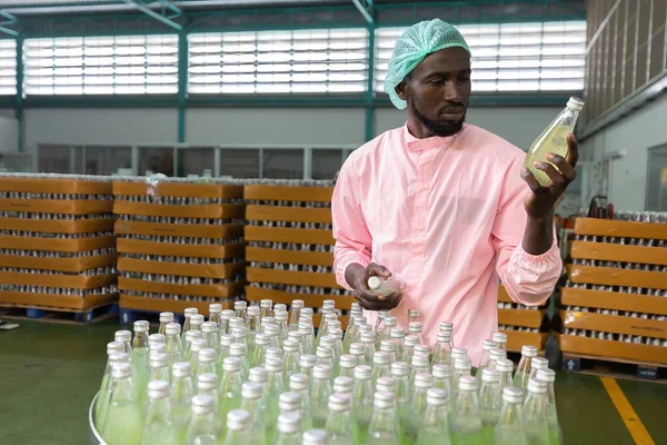 Trabajador Africano Fábrica Que Sostiene Mira Botella Jugo Verde Bebida — Foto de Stock