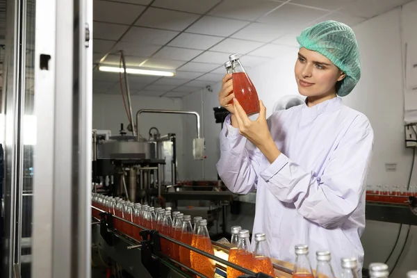 饮料制造厂的年轻女工喝罗勒种子酒检查质量 — 图库照片