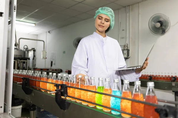 young woman factory worker pick up basil seed drink for checking quality in beverage factory