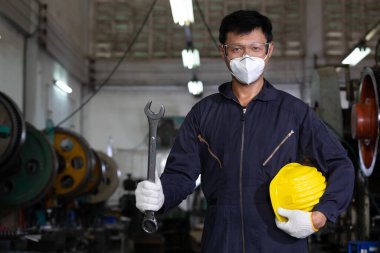 miğfer ve yüz maskesi takan İngiliz anahtarı tutan bir mühendis ya da tamirci.