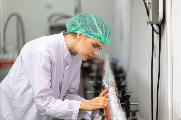 young woman factory worker looking basil seed drink for checking quality in beverage factory