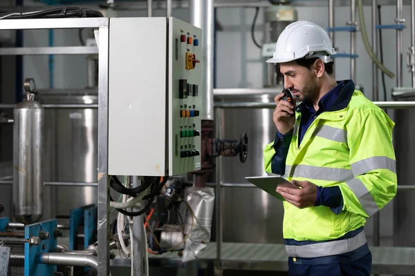 engineer or factory worker using tablet computer and walkie talkie for finding how to use machine control panel in factory