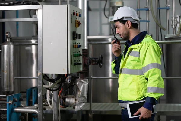 engineer or factory worker using tablet computer and walkie talkie for finding how to use machine control panel in factory