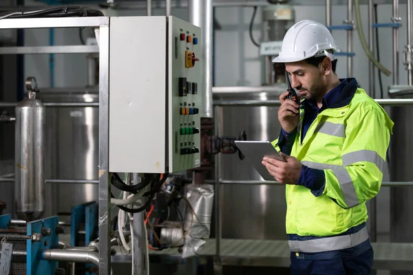 engineer or factory worker using tablet computer and walkie talkie for finding how to use machine control panel in factory
