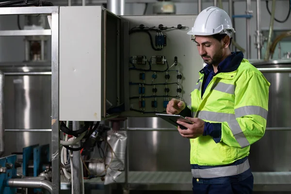 engineer or factory worker using tablet computer for finding how to use machine control panel in factory