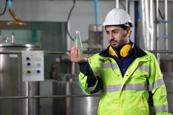 engineer or factory worker holding green basil seeds drink for checking quality in beverage factory