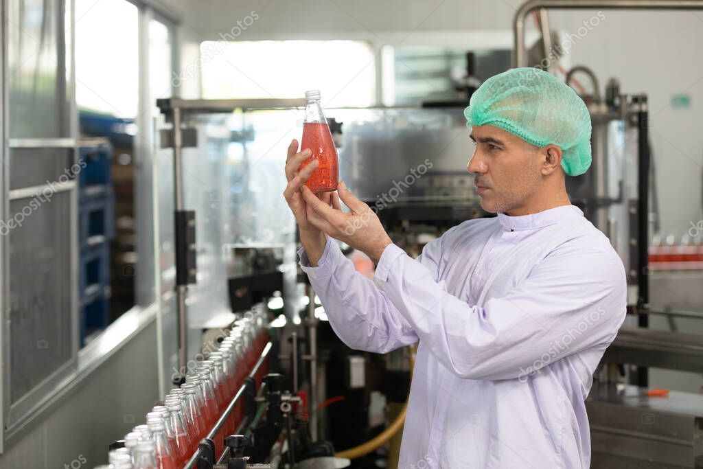 male factory worker holding red basil seeds drink for checking quality in beverage factory