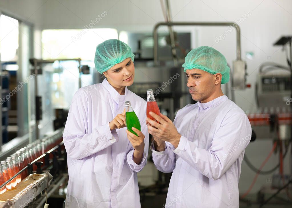 two factory workers talking about project and checking quality of basil seed drink in beverage factory