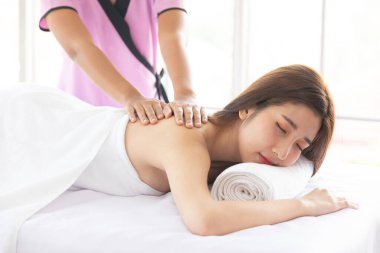 Genç Asyalı kadın güzellik salonunda uyuyor ve masajdan zevk alıyor.