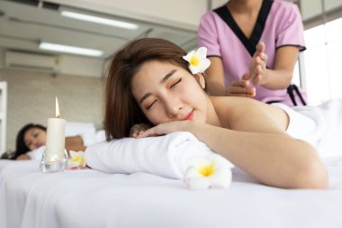 Genç Asyalı güzel kadın güzellik salonunda eğleniyor, uyuyor ve masaj yaptırıyor.