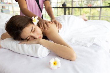 Genç Asyalı güzel kadın güzellik salonunda eğleniyor, uyuyor ve masaj yaptırıyor.