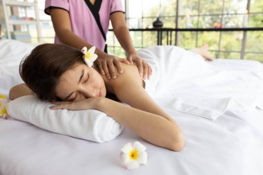 Genç Asyalı güzel kadın güzellik salonunda eğleniyor, uyuyor ve masaj yaptırıyor.