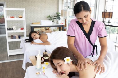 Genç Asyalı masör spa salonundaki kadın müşteriye masaj yaptırıyor.
