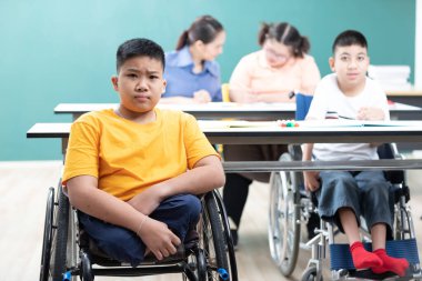 Sınıfta tekerlekli sandalyede oturan Asyalı engelli çocukların portresi