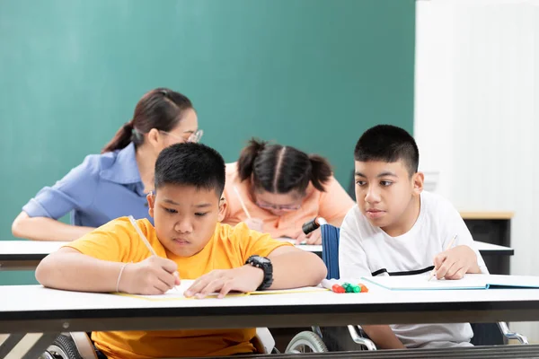 asian disabled kids or autism child learning looking and writing at desks in classroom